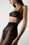 Front view of sheer black tights with embroidered stars, elongating the legs